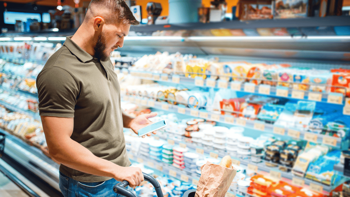 Zdjęcie przedstawiające mężczyznę, który wybiera zdrowe produkty spożywcze z półki sklepowej.